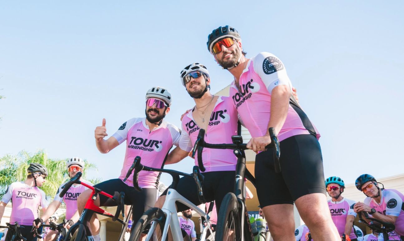 Riders in pink Tour de Friendship jerseys smiling together before the ride