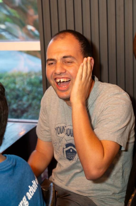 A young man laughing at a Young Adult Club dinner